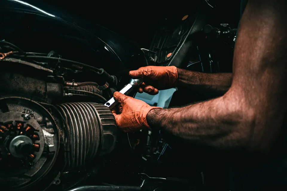 Mains gantées qui serrent un écrou sur le moteur d’une moto